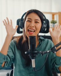 Happy asia girl record a podcast with headphones and microphone Happy asia girl record a podcast with headphones and microphone look at camera talk and take a rest in her room. Female podcaster make audio podcast from her home studio, Stay at house concept.